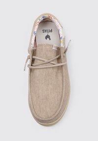 Zapatilla de tela beige con forma redondeada, detalles de cordones y un forro interior con un patrón floral. Suela flexible y hardware mínimo.