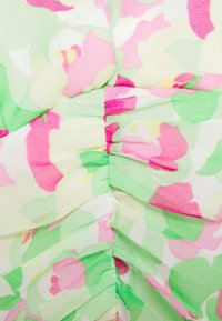 Blumenerstoff mit pinken und grünen Mustern, leicht und strukturiert im Griff. Das Design umfasst Falten und weiche Plissee-Details.