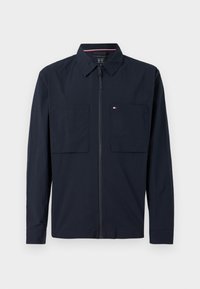 Ναυτικό ζακέτα με φερμουάρ, με ανοιχτό γιακά, δύο μπροστινές τσέπες και ένα μικρό λογότυπο στην αριστερή τσέπη. Λείος υφιστάμενος, μακριά μανίκια.