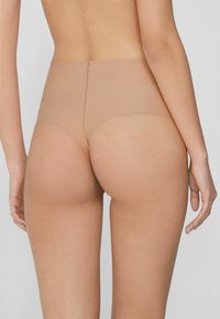 Beige naadloze hoge tailleslip met een gladde textuur, biedt volledige bedekking en minimale zichtbare lijnen, gedetailleerd met een smalle tailleband.