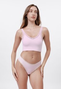 Bralette de malha rosa claro com acabamento em renda, combinado com roupa interior com detalhes em renda, apresentando um design ajustado e textura suave.