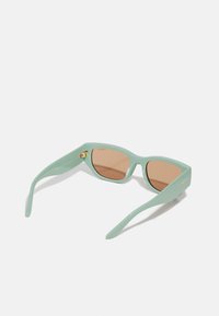 O pereche de ochelari de soare mint green cu lentile maro, având un design elegant, unghiular și accente de hardware aurii pe temple.