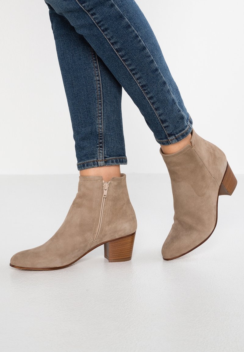 Beżowe zamszowe botki za kostkę z lekko spiczastym noskiem i 5 cm obcasem w kształcie stosu, z bocznym zamkiem błyskawicznym i gładką fakturą.
