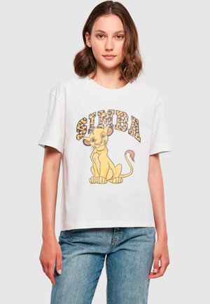 T-shirt en coton blanc avec un dessin de lion en cartoon au pelage fauve, étiqueté "SIMBA" en lettres imitation léopard jaunes et brunes. Manches courtes.