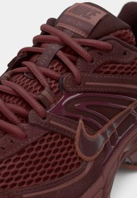 Bordové tenisky Nike s textilom a semišovými materiálmi, zložitým šnurovaním, lesklými akcentmi a výrazným logom na jazyku.