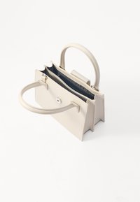 Beige læder håndtaske med to topgreb. Har et struktureret design, tryklukning og en mørk indvendig foring med synlig branding.