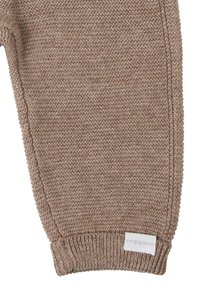 Braune Strickhose mit gerippten Bündchen und glatter Textur; verfügt über ein kleines weißes Etikett mit der Aufschrift "noppies" an der Seite.