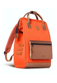 Sac à dos en tissu orange avec des accents en bronze, comprenant une poche à fermeture éclair à l'avant et des poignées ; présente un tissage latéral et une forme structurée.