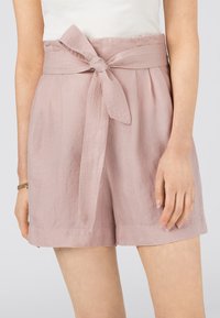 Vaaleanpunaiset shortsit, jotka on valmistettu tekstuuri-kankaasta. Ne sisältävät leveän vyötärönauhan, jossa on solmittu rusetti, pleated-vatsan ja rento istuvuus.
