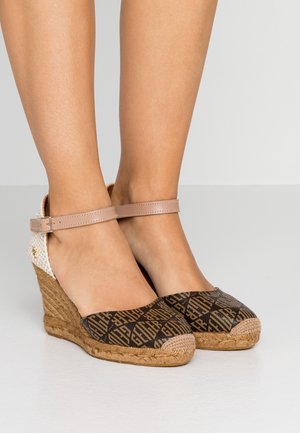 Espadrilles à talon compensé marron et noir avec un dessus en textile à motifs, semelle en jute tressé et une sangle de cheville beige. Design texturé et à bout ouvert.