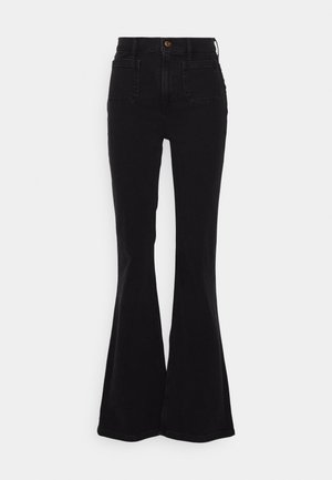 Mustad flared teksased, kõrge vöökoht, valmistatud denimkangast. Omab tagakotte ja peeneid õmblusdetailide. Üldiselt sile tekstuur.