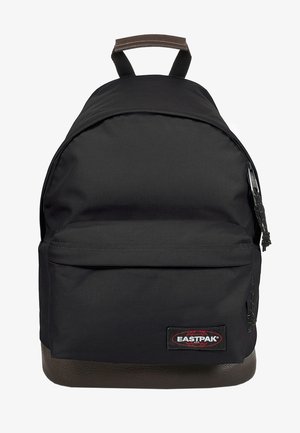 Sac à dos Eastpak noir en tissu durable, de forme arrondie, avec une poche à zip à l'avant, une base en similicuir et une poignée supérieure pour le transport.