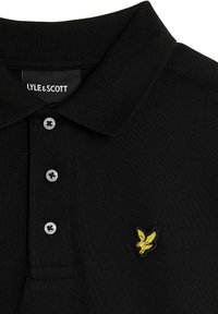 Zwarte poloshirt van textuurstof, met een knoopsluiting met drie knopen en een gele geborduurde logo van een vogel op de borst.