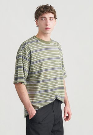 Gestreiftes T-Shirt in Olivgrün, mit unterschiedlich breiten weißen und grauen Streifen, kurzen Ärmeln und Rundhalsausschnitt. Auffälliges Logo auf der Brust.