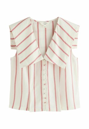 Blouse blanche sans manches avec des rayures verticales rouges et un grand col, associée à un pantalon blanc taille haute avec des rayures noires et un lien à nouer devant.