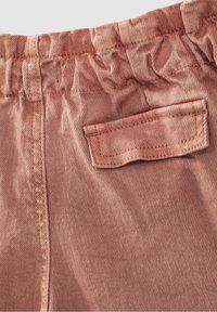 Pantalons en coton rose poussiéreux avec ceinture élastique, dotés d'une poche arrière plate et d'une texture à fines côtes. Vue rapprochée du tissu et des coutures.