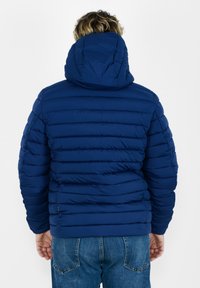 Giacca a vento blu con cappuccio, caratterizzata da un design trapuntato e strisce orizzontali, realizzata in un materiale liscio e leggero.