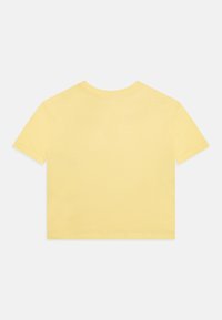 Krátký rukáv, zkrácený tričko z jemné žluté bavlny. Má jednoduchý kulatý výstřih a hladký, jemný povrch bez ozdob.