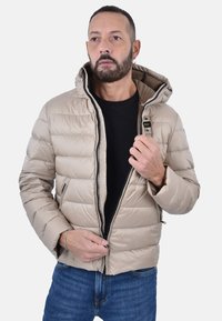 Giacca puffer beige con cappuccio, chiusura con zip e design a righe orizzontali. Presenta due tasche laterali e una fodera interna nera.