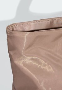 Bolsa de tecido rosa suave com um leve brilho, apresentando uma textura suave e costura cuidada ao longo da borda superior. Sem hardware ou acentos adicionais.