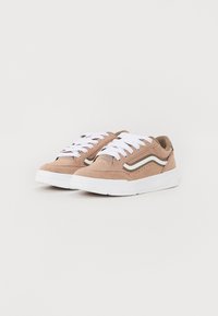 Zapatillas de ante marrón con cordones blancos, que cuentan con un diseño de franja lateral y perforaciones para ventilación. Suela de goma blanca con textura.