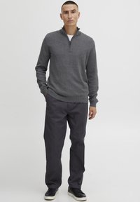 Gray zip-up sweater with long sleeves, paired with dark gray pants and black sneakers. Simple design, smooth texture, and casual fit.