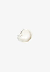 Crème blanche avec une texture lisse et brillante, appliquée en un étalement circulaire sur un fond neutre.
