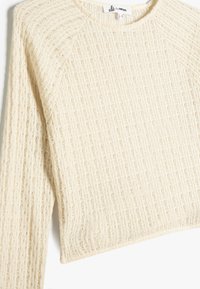 Lichtbeige cropped trui met ribbeltextuur en lange mouwen. Heeft een ronde hals en een eenvoudig ontwerp, gemaakt van zacht gebreid materiaal.