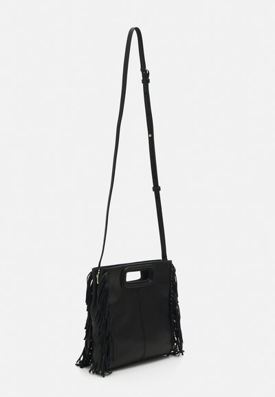 Black leather crossbody bag with fringe detail on sides, flat shape, adjustable strap, and top handle. Smooth texture and minimalist design.