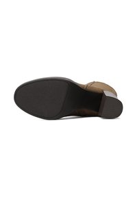 Stivale alla caviglia in suede marrone con suola texturizzata, caratterizzato da un tacco basso e dettagli cuciti lungo i lati.
