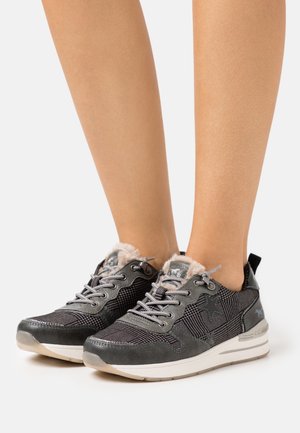 Šedá a černá teniska s textilním svrškem, plyšovou podšívkou, texturovanými vzory, tkaničkami a bílou gumovou podrážkou. Má hvězdný dekorativní prvek.