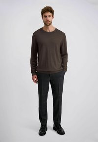 Dunkelbraunes Langarmshirt mit Rundhalsausschnitt, kombiniert mit anthrazitgrauen karrierten Hosen und schwarzen Schnürschuhen. Glatte Stofftextur.