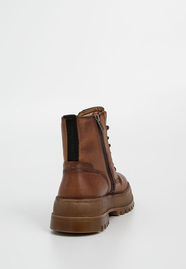 Botín de cuero marrón hasta el tobillo con una superficie texturizada, cierre de cremallera lateral y suela de goma. Presenta tejido elástico en la parte trasera para facilitar su uso.