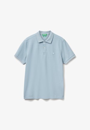 Camisa polo de manga corta en azul claro con botones y pequeño logo bordado en el lado izquierdo del pecho, dispuesta sobre un fondo blanco.