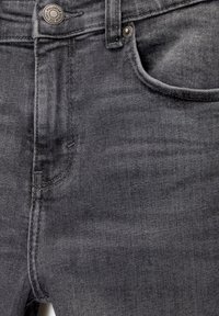 Gros plan sur un jean en denim gris foncé montrant la poche avant, un bouton avec la marque "Pull&Bear Denim" et des coutures détaillées.