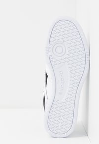 Weißer Sneaker mit einer strukturierten Gummisohle, ausgestattet mit einem schwarzen Akzent und einem Markenlogo. Glattes Obermaterial mit einem Low-Top-Design.