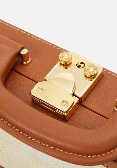 Brown leather handbag closure with shiny gold hardware, featuring a clasp mechanism and decorative accents. The texture is smooth with visible stitching.