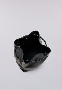 Czarna torba typu tote z miękką fakturą, otwartym górnym wejściem i regulowanymi uchwytami. Posiada wewnętrzną kieszeń na zamek dla bezpiecznego przechowywania.