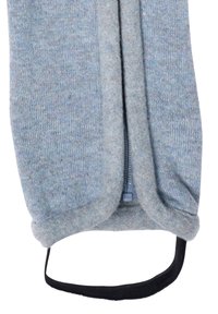 Ljusblå stickad plagg med mjuk textur, med en dragkedja fram och ett svart tygband. Märkbar färgvariation genom hela materialet.