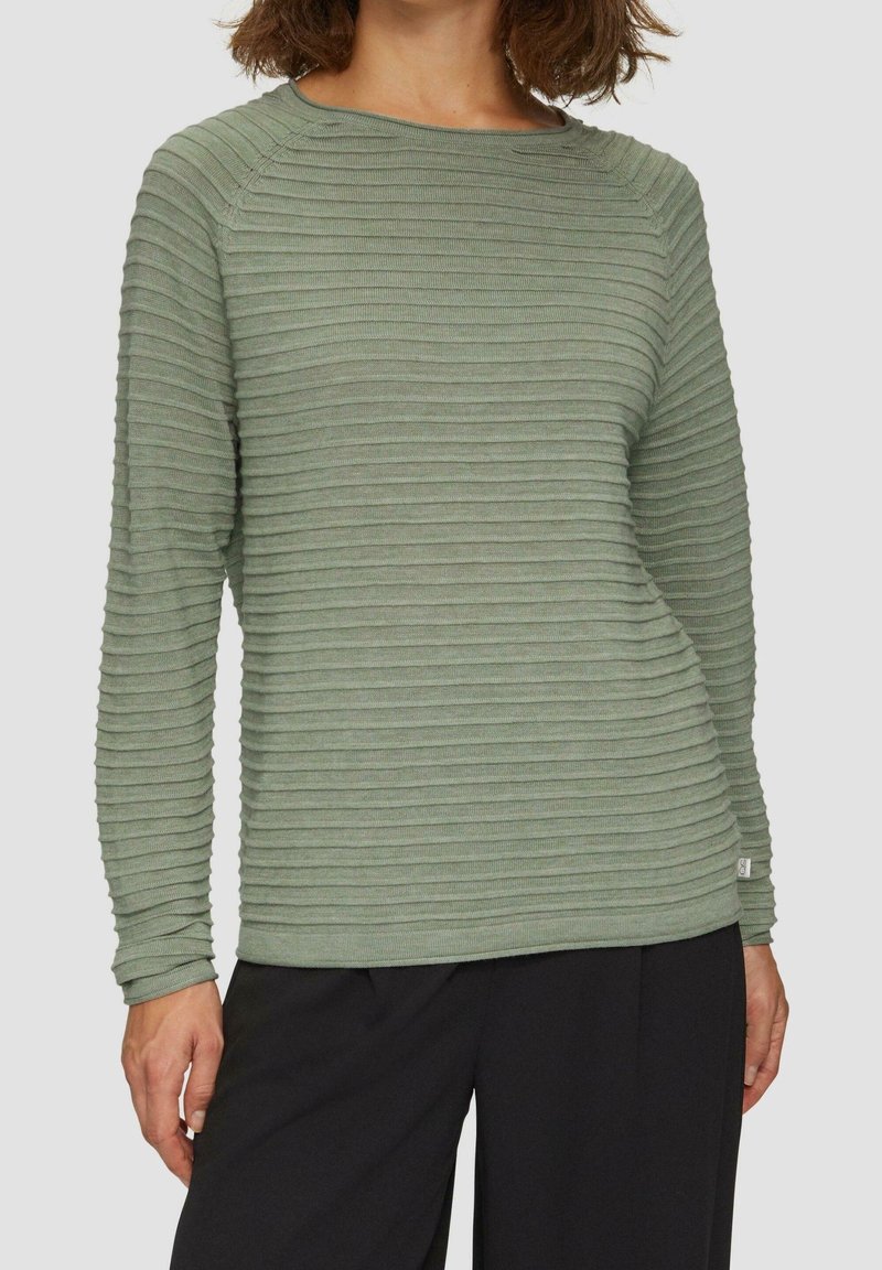 Grön ribbad långärmad topp med rund halsringning, med strukturerade horisontella ränder och en liten logotypetikett i sidsömmen.