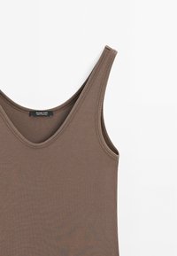 Bruine geribde tanktop met brede schouderbanden, gebogen halslijn en een gladde textuur. Merklabel zichtbaar in het midden.