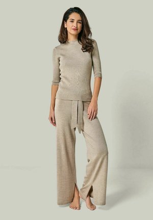Knit beige top with short sleeves paired with wide-leg beige pants featuring a tie belt and side slits, showcasing a soft texture.