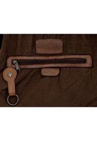 Brown leather and fabric bag section with horizontal zipper pocket, stitched leather key holder with metal ring, and embossed "Gusti Leder" label.