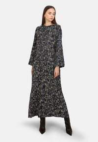 Robe longue bleu marine avec un motif floral, dotée de manches longues et d'un col rond. Fabriquée en tissu léger, elle descend jusqu'à la cheville.