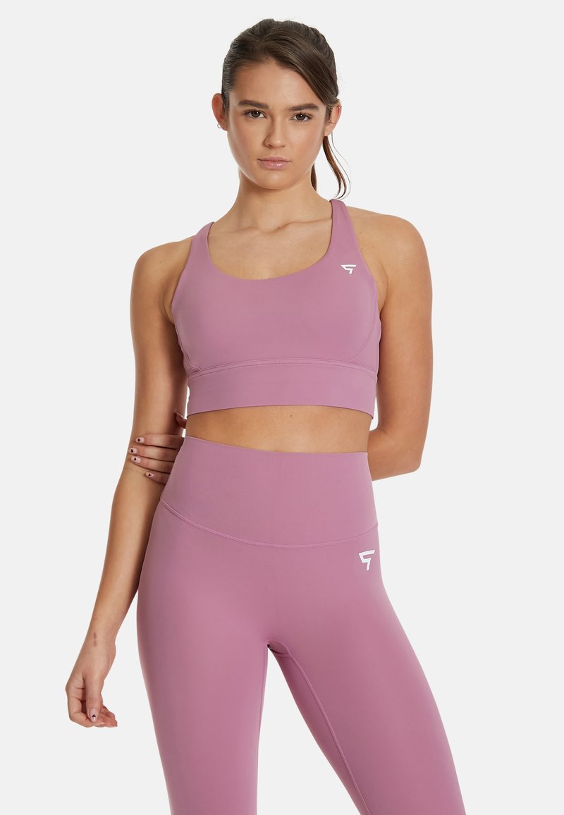 Ljubičasti sportski brus i set visokih tajica od glatkog, rastezljivog materijala. Ima naglasak na logo i bešavni dizajn za udobnost.