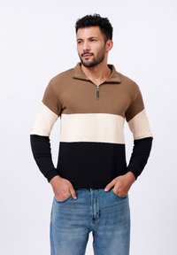 Sweatshirt zippé pour homme en panneaux marron, crème et noir. Doté d'un col montant et de poignets côtelés. Tissu en coton texturé. Coupe décontractée.
