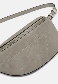 Borsa a spalla in suede grigia con forma curva. Presenta una zip superiore e un logo del marchio in rilievo. La tracolla è regolabile per una vestibilità ottimale.