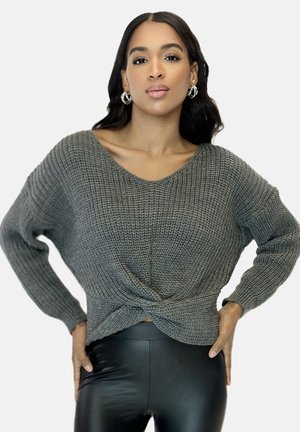 Grijs gebreid sweater met wijde V-hals, gestructureerde stof en geknoopt detail aan de voorkant, gecombineerd met zwarte legging.