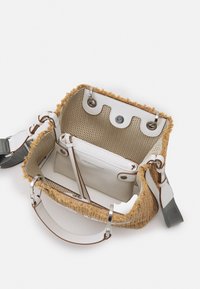 Sac tissé beige avec une finition texturée, accents en cuir blanc et bordure marron. L'intérieur comprend un compartiment blanc et une fermeture à pression.