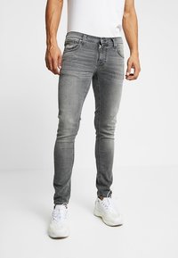 Grå denimjeans med slim fit, framfickor, subtila blekningar och kontrasterande sömmar, parat med vita träningssneakers.